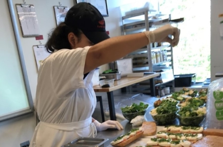A FareStart student sprinkling salt on bruschetta