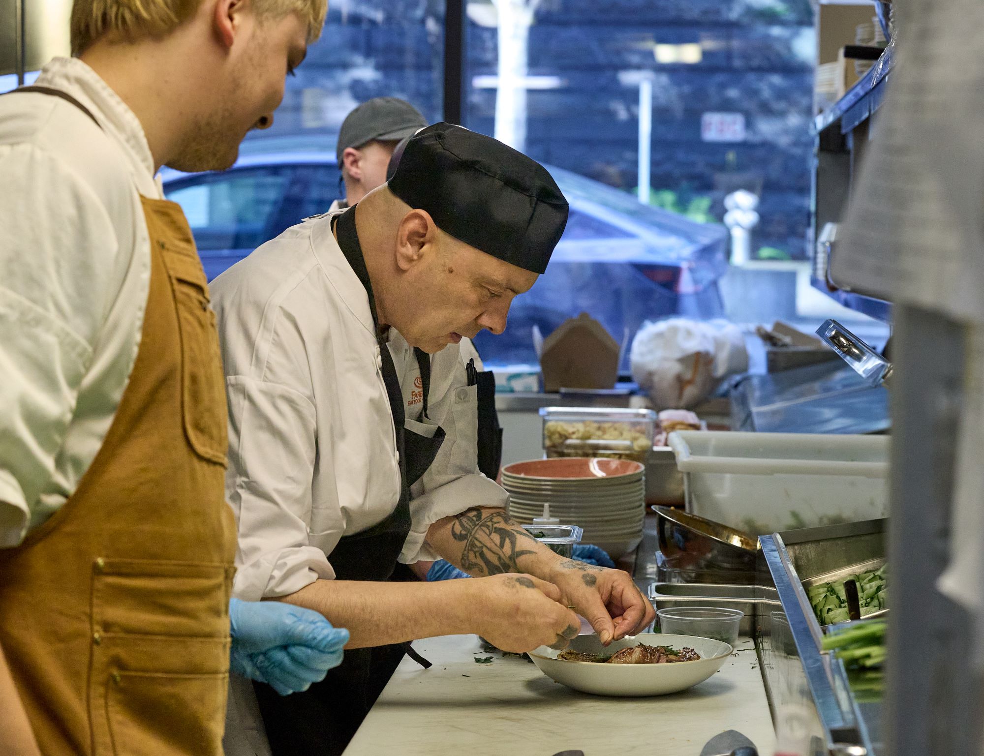 Julio, FareStart Food Pathways Program plating a meal at Guest Chef Night