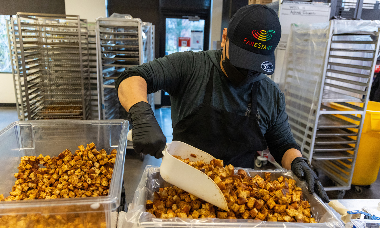 A masked FareStart employee weighs croutons. Photo by Meryl Schenker.