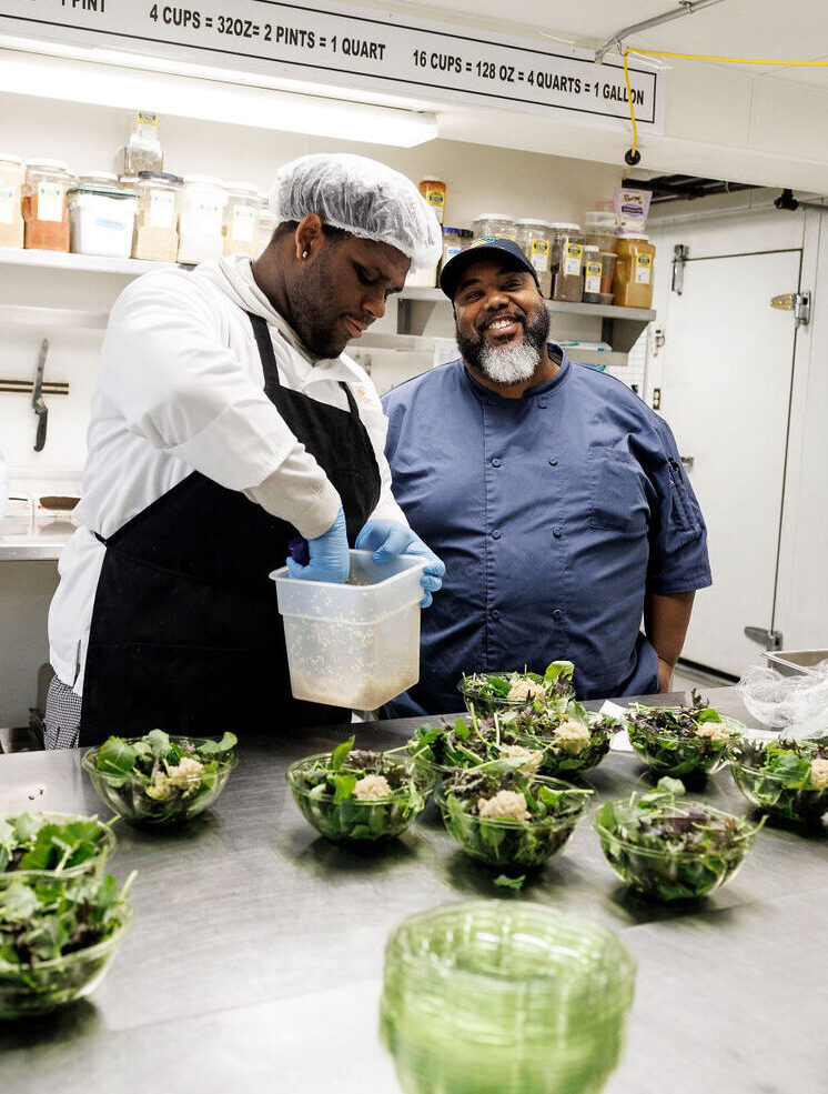 Food Pathways Program student making salads with a smiling chef trainer