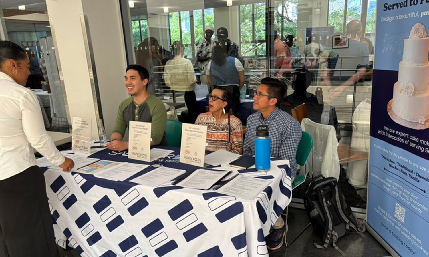 Three people talking to a job seeker at a job fair