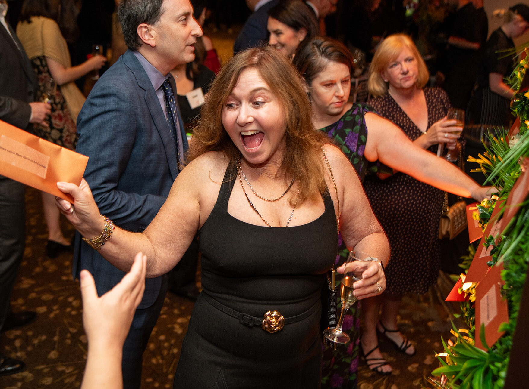 An excited FareStart 33rd Annual Gala attendee smiling and excitedly waving an envelope