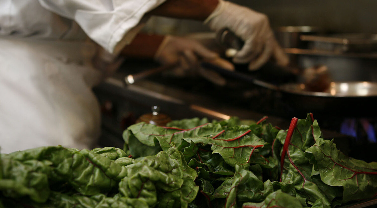 Chef preparing a dish with leafy green chard