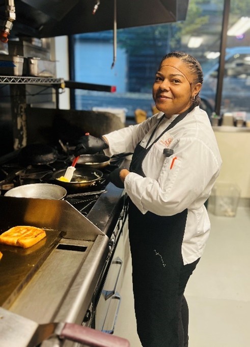 FareStart graduate Jennifer in a commercial kitchen setting during a FareStart Guest Chef Night