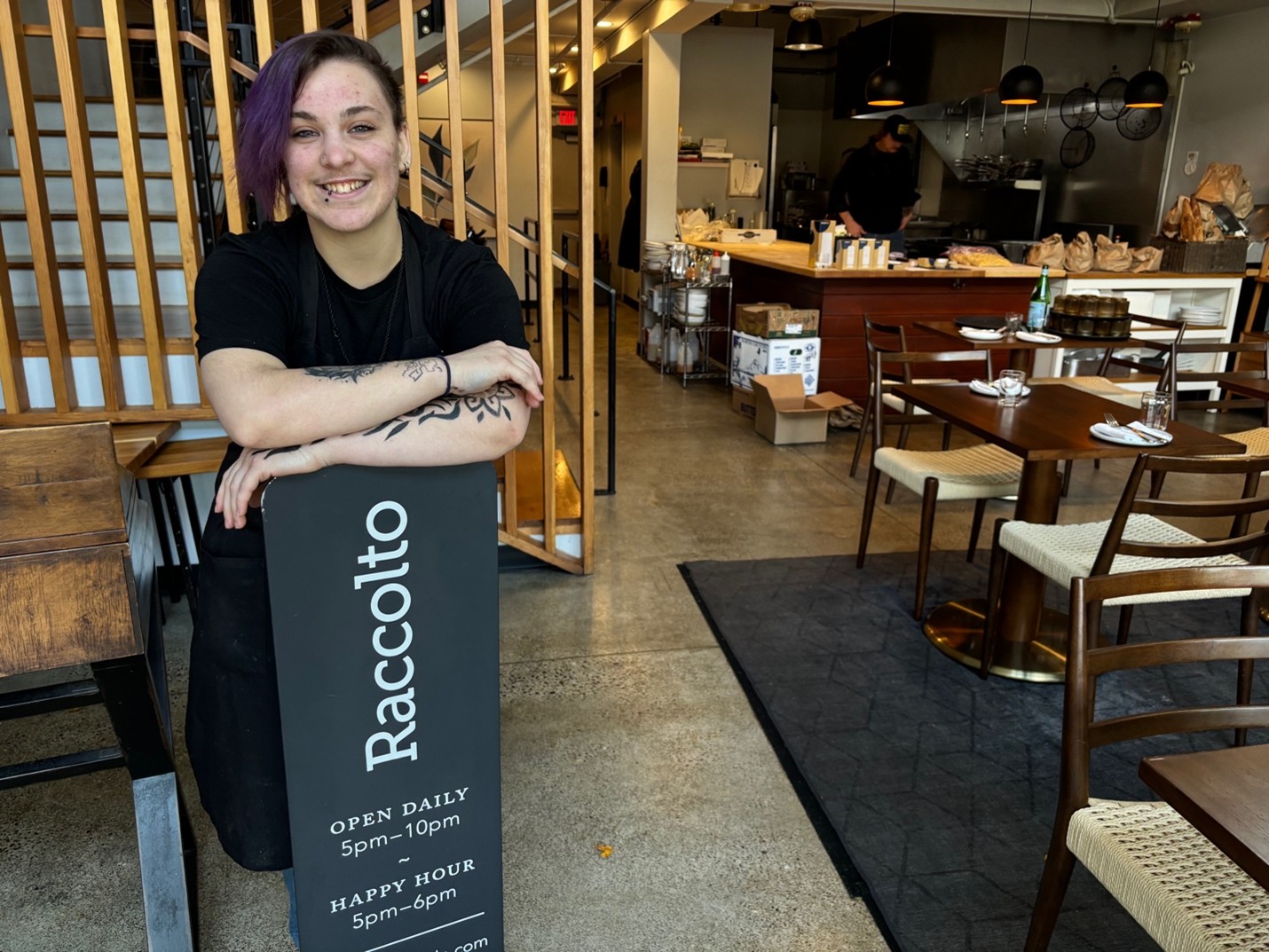 Aries, a FareStart graduate, posing with a Raccolto sign