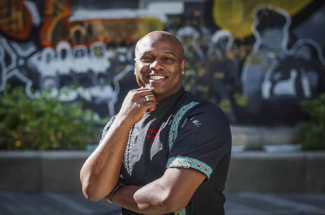 Chef Trey Lamont smiling with his hand resting on his chin