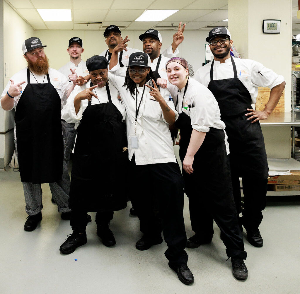 Students and graduates posing in a commercial kitchen setting