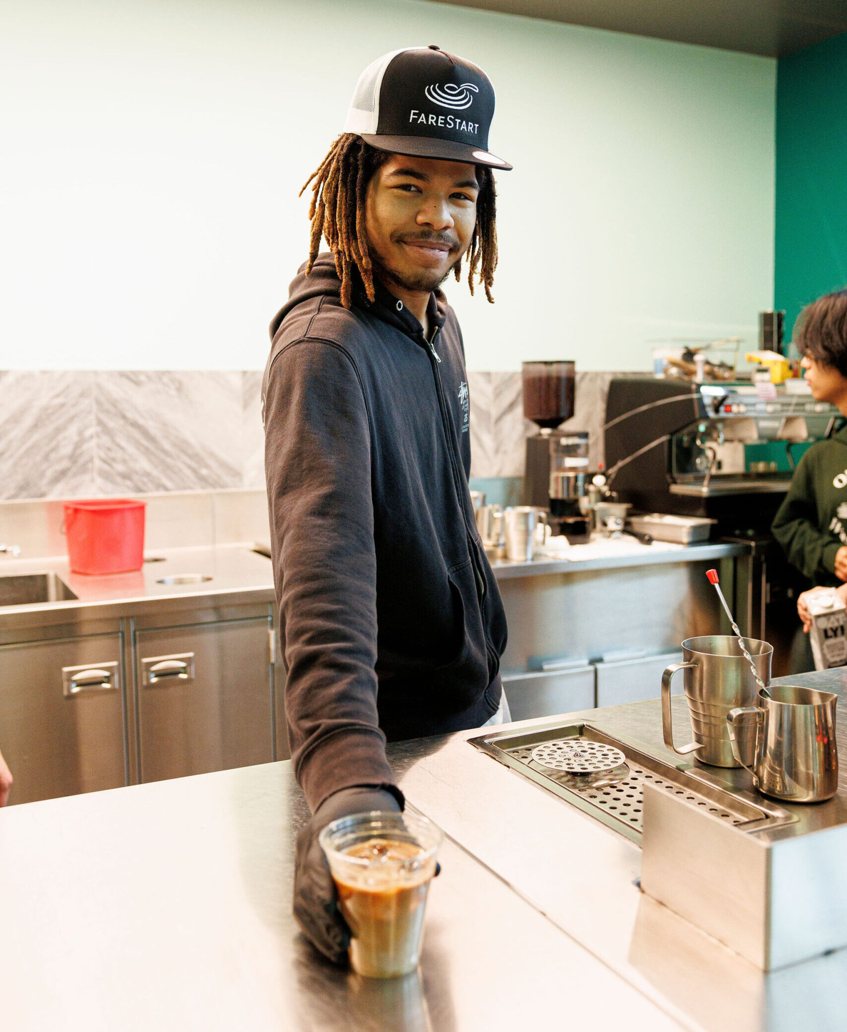 Barista & Customer Service Program student holding an iced coffee and smiling