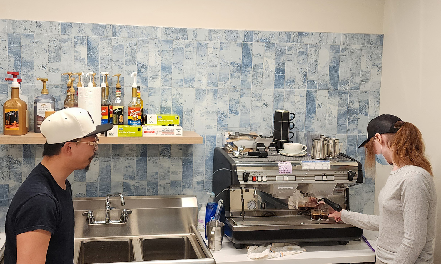 Barista & Customer Service Program student learning how to pull an espresso shot on an espresso machine with a FareStart trainer