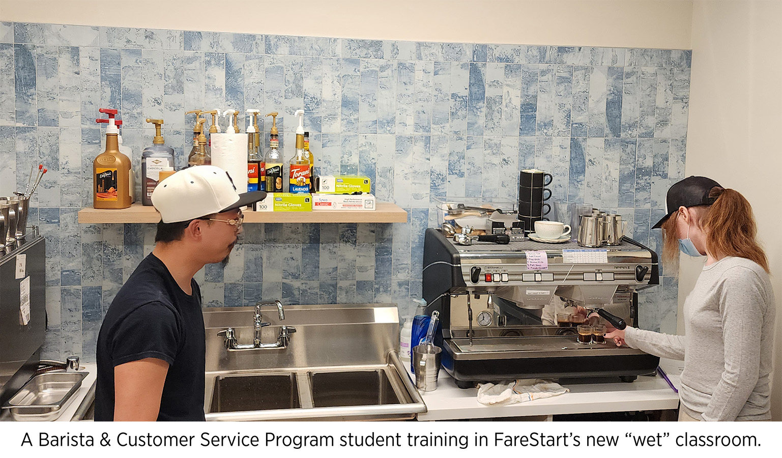Barista & Customer Service Program student learning how to pull an espresso shot on an espresso machine with a FareStart trainer
