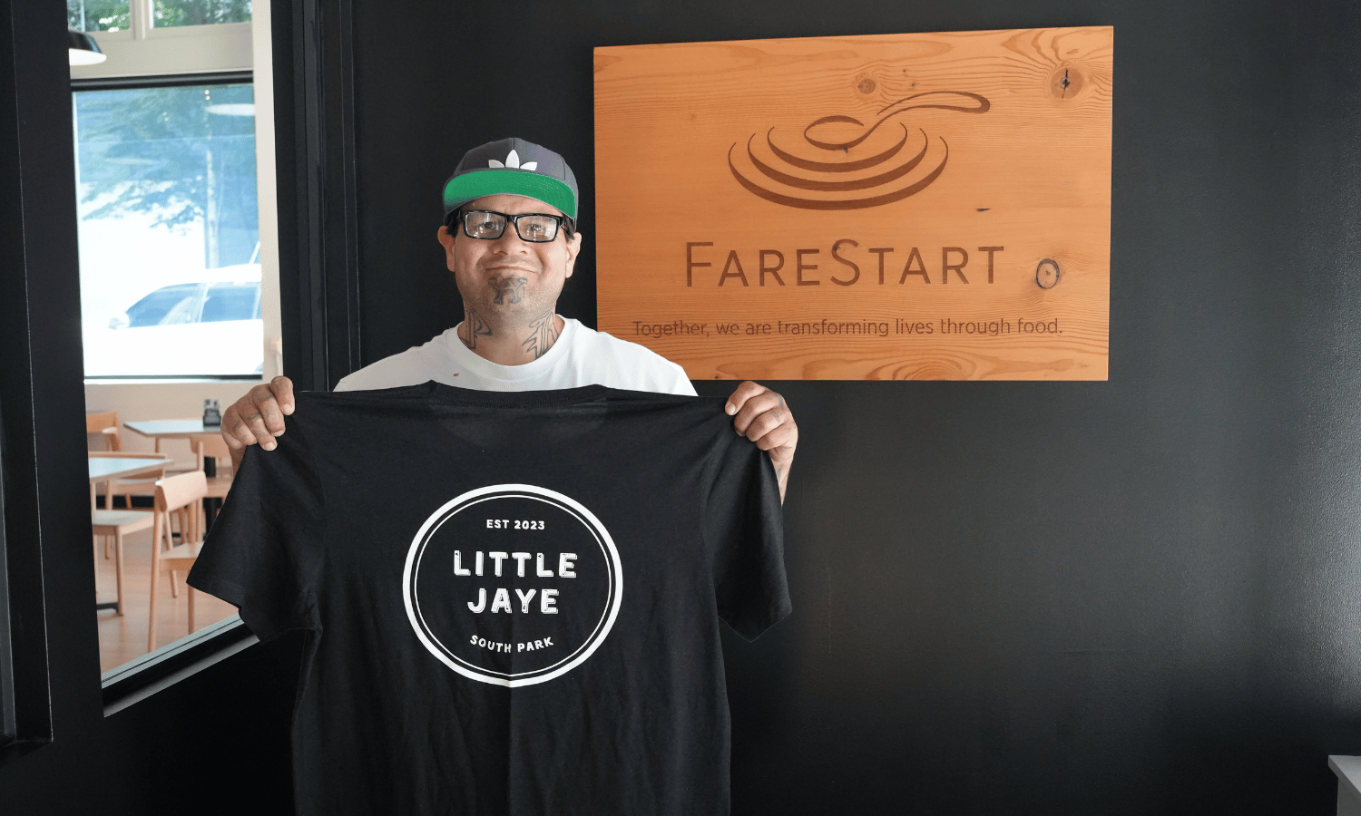 Damian in FareStart restaurant holding Little Jaye Shirt