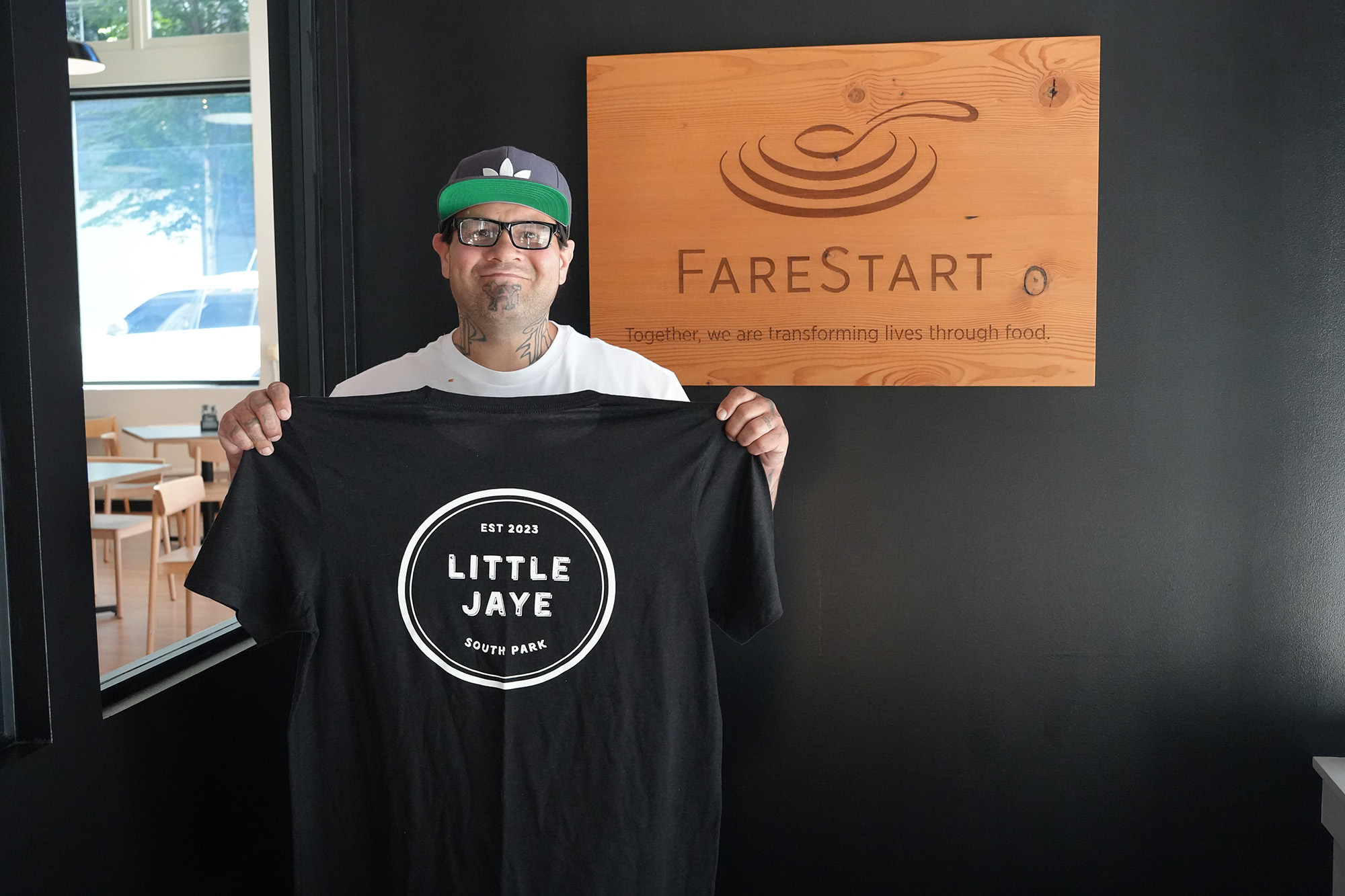 Damian in FareStart restaurant holding Little Jaye Shirt